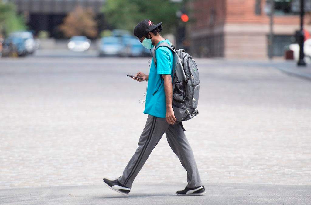 A man wears a face mask as he walks along a street in Montreal, Sunday, July 26, 2020, as the COVID-19 pandemic continues in Canada and around the world.
