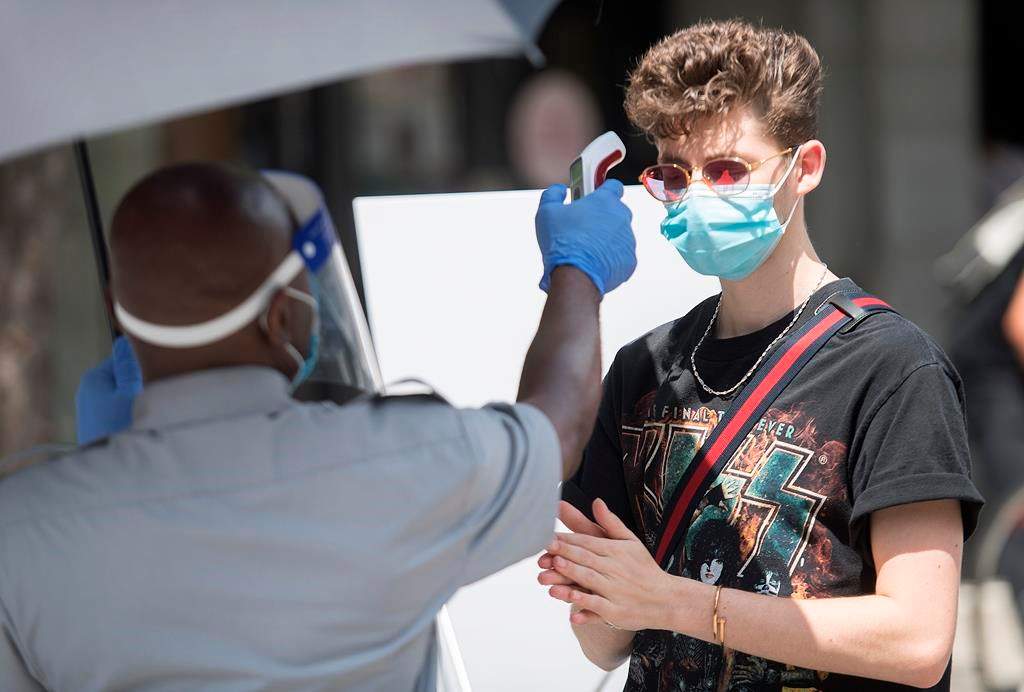 A man has temperature checked before entering a store in Montreal, Saturday, July 25, 2020.