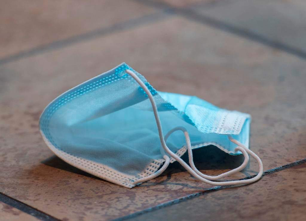 A discarded face mask is shown on the floor of a food court in a shopping mall. 