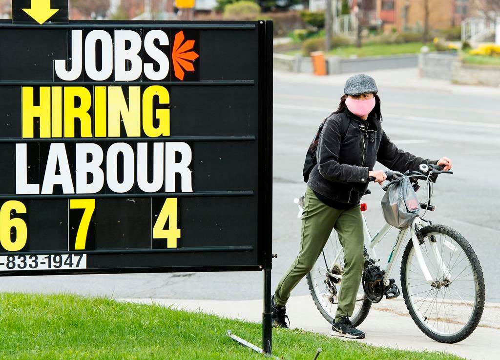 A woman checks out a jobs advertisement sign during the COVID-19 pandemic in Toronto on April 29, 2020.
