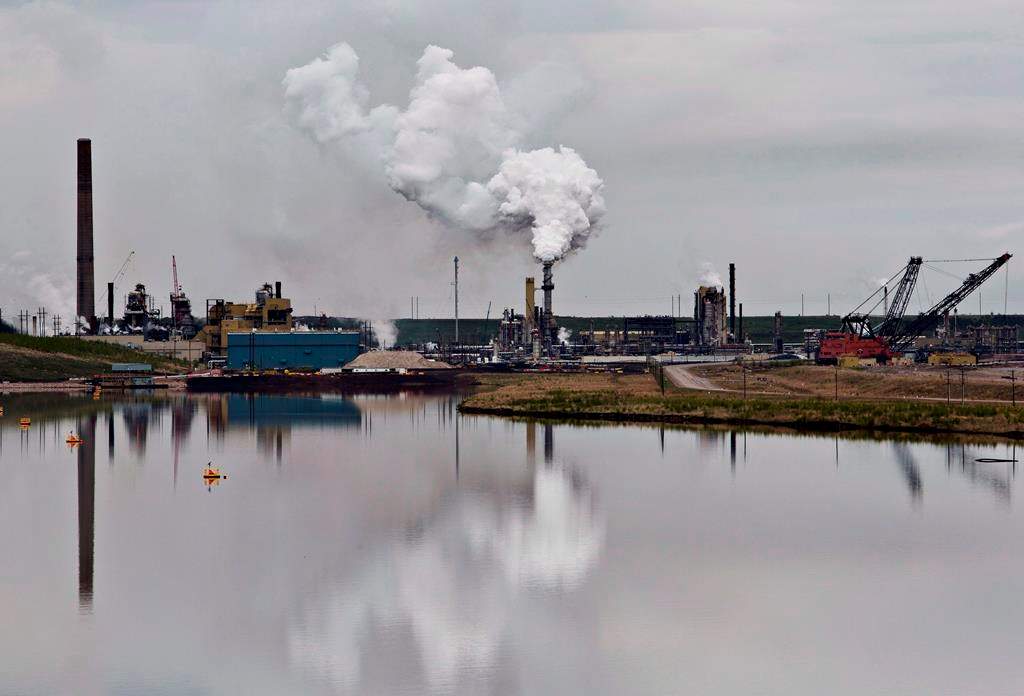 An oilsands extraction facility is reflected in a tailings pond near the city of Fort McMurray, Alta., on June 1, 2014. Frankfurt-based Deutsche Bank is joining a lengthening list of European lenders and insurance companies that say they won't back new oilsands projects.