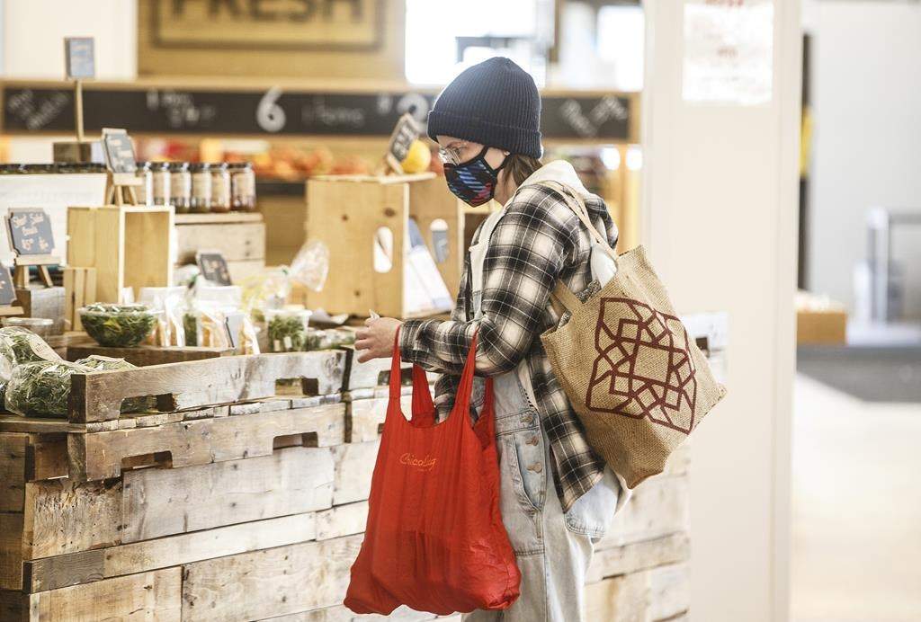 A shopper wearing a mask buys groceries at a sparse farmers market in Edmonton on Sunday March 22, 2020. 