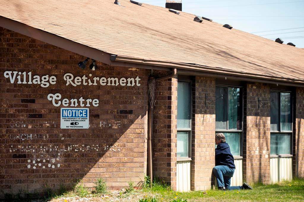 A woman tries to speak to her mother through a window at Orchard Villa Care home, in Pickering, Ont. on Saturday, April 25, 2020.