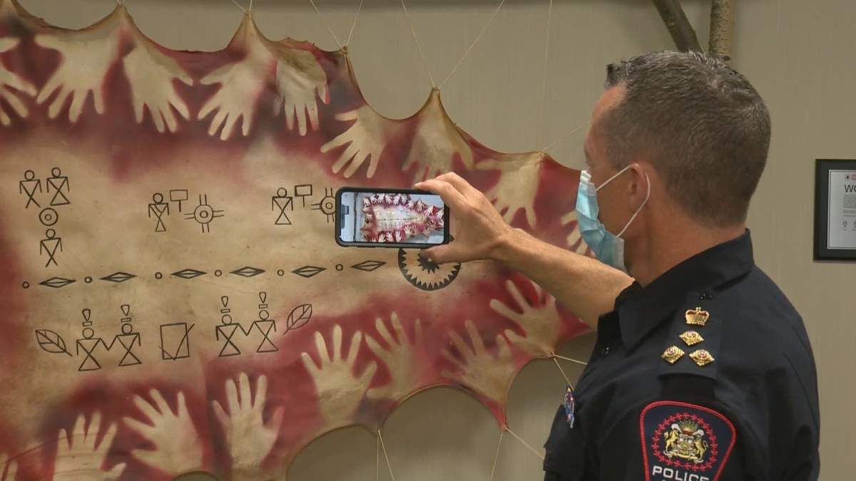 Calgary Police Service Chief Mark Neufeld uses the USAY AR app to hear more of the story behind the mural.