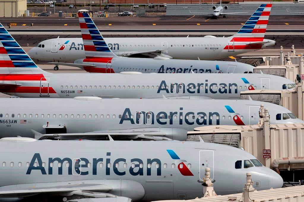  In this Wednesday, March 25, 2020, file photo, American Airlines jets sit idly at their gates as a jet arrives at Sky Harbor International Airport in Phoenix. 