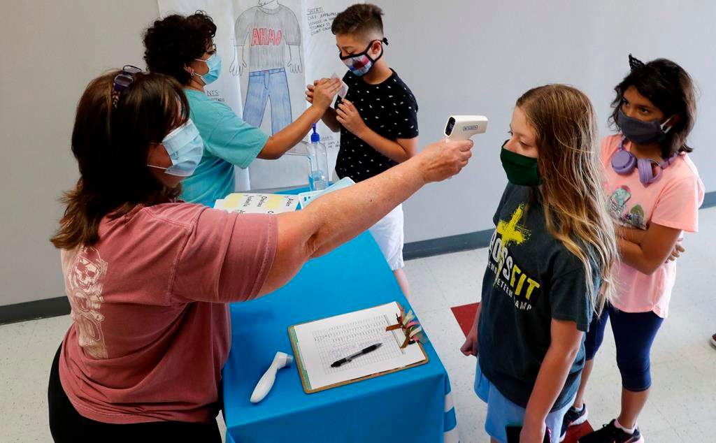 In this Tuesday, July 14, 2020 file photo, teachers check students before a summer STEM camp at Wylie High School in Wylie, Texas.