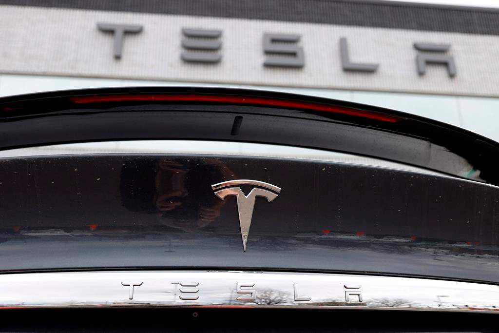 FILE - In this April 26, 2020 photograph, the company logo shines off the rear deck of an unsold 2020 Model X at a Tesla dealership in Littleton, Colo. Tesla is reassuring its 55,000 employees that it hasn't had a major coronavirus outbreak at company facilities worldwide. In an email to workers sent Wednesday, July 15, the company said that since January it has had fewer than 10 cases of the virus that causes COVID-19 that were transmitted in the workplace.(AP Photo/David Zalubowski, File).