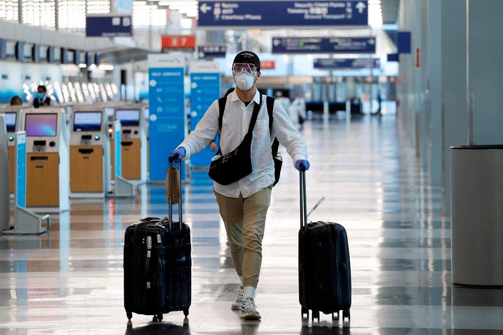 FILE - In this June 16, 2020 file photo, a traveler wears a mask and protective goggles as he walks through Terminal 3 at O'Hare International Airport in Chicago. United Airlines says its face mask requirement now extends to ticket counters and airport lounges. United said Wednesday, July 22 that it might ban violators from flying on its planes. United and all other major U.S. airlines already require passengers to wear masks during flights. (AP Photo/Nam Y. Huh, File).