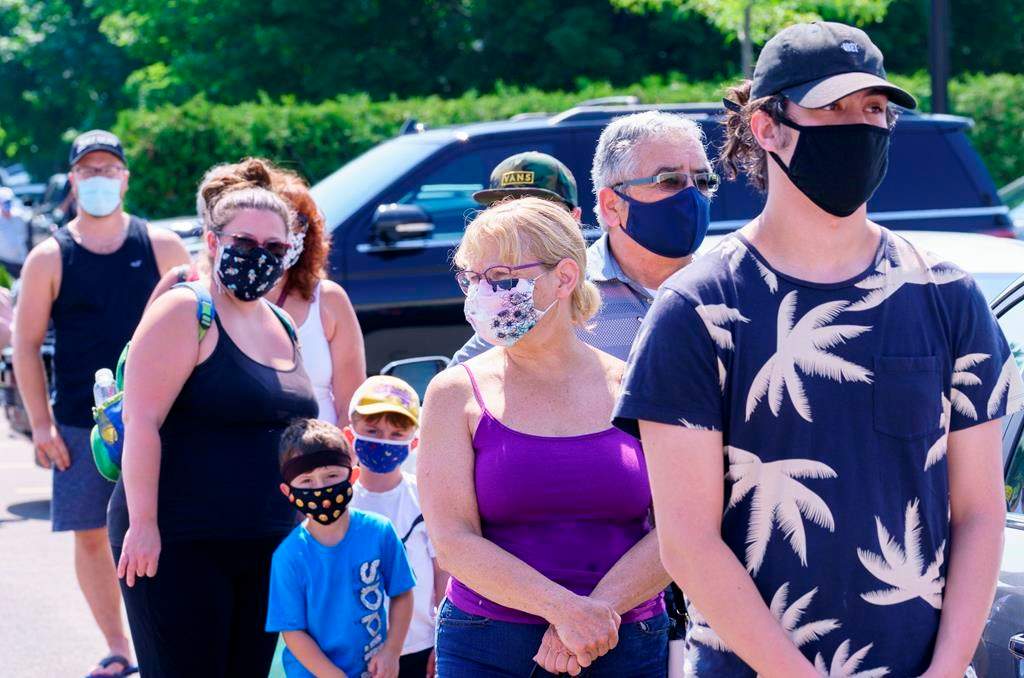 People line up to enter a mobile COVID-19 test clinic in Mercier, Que., Thursday, July 9, 2020. A small community south of Montreal is making mask-wearing mandatory beginning today inside all commercial businesses following a COVID-19 outbreak authorities say is tied to a house party.THE CANADIAN PRESS/Paul Chiasson.
