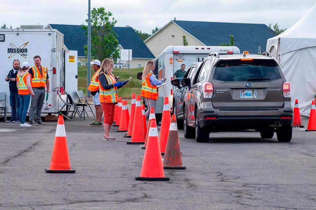 Volunteers examine the documents of motorists who just came off the Confederation Bridge in Borden-Carleton, P.E.I., Friday, July 3, 2020. s.