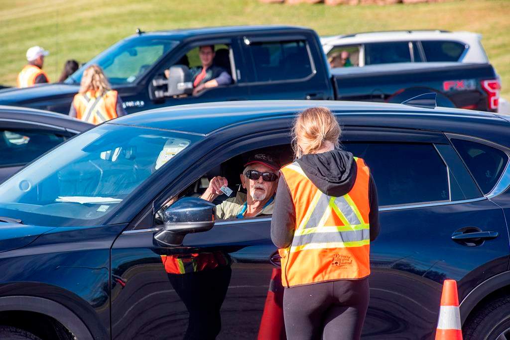 A motorist shows his identification to a provincial worker at the Confederation Bridge in Borden-Carleton, P.E.I., Friday, July 3, 2020. Prince Edward Island's chief medical officer of health is strongly urging people to wear non-medical face masks indoors but so far isn't recommending they be mandatory.THE CANADIAN PRESS/Brian McInnis.