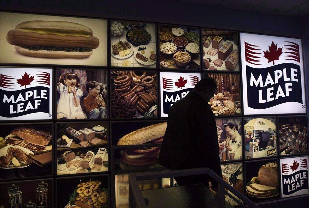 A Maple Leaf Foods employee walks past a Maple Leaf sign at the company's meat facility in Toronto on Monday, Dec. 15, 2008.