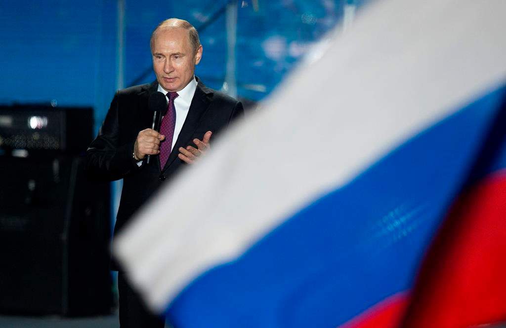 FILE - In this file photo dated Wednesday, March 14, 2018, Russian President Vladimir Putin speaks in front of a Russian National flag in Sevastopol, Crimea.
