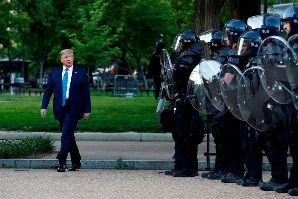 FILE – In this June 1, 2020, file photo President Donald Trump walks past police in Lafayette Park after visiting outside St. John\’s Church across from the White House in Washington. When it comes to squelching protests in Democrat-run cities, Trump is eager to send in federal troops and agents — even when local leaders are begging him to butt out.