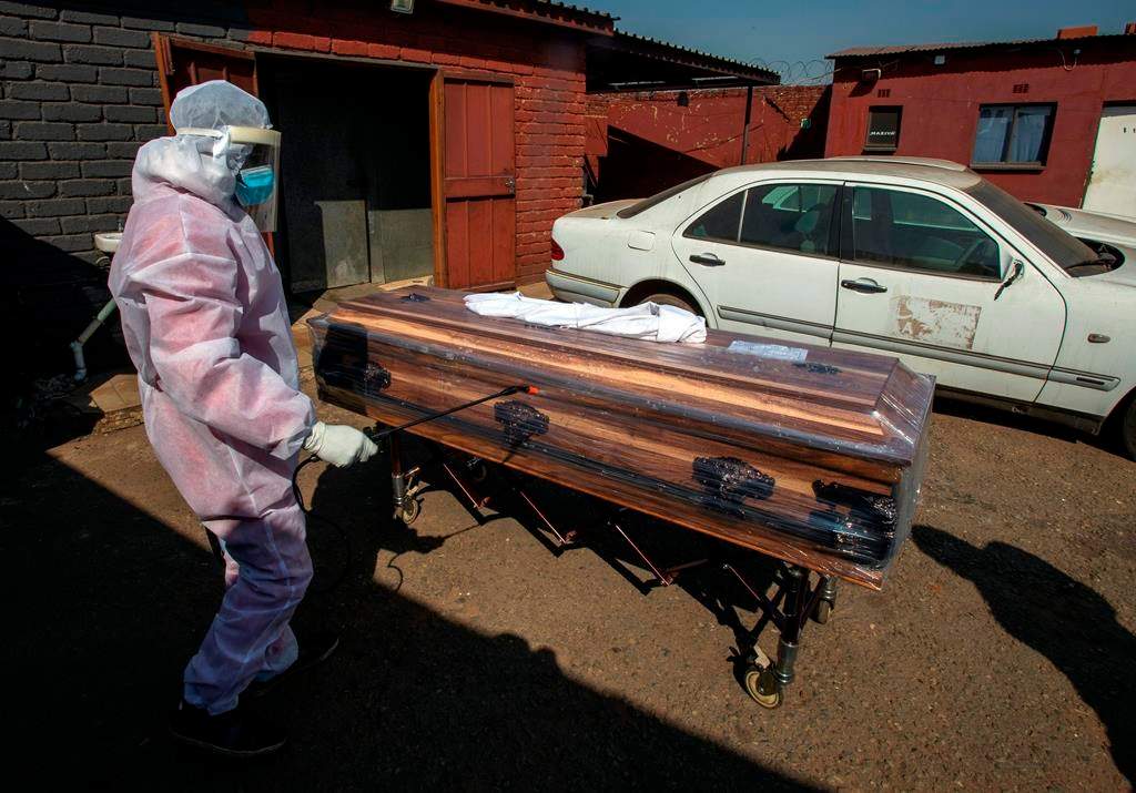 A funeral home worker in a protective suit disinfects a coffin carrying a woman who died from COVID-19 as they prepare for a funeral in Katlehong, near Johannesburg, South Africa, Tuesday, July 21, 2020. (AP Photo/Themba Hadebe)