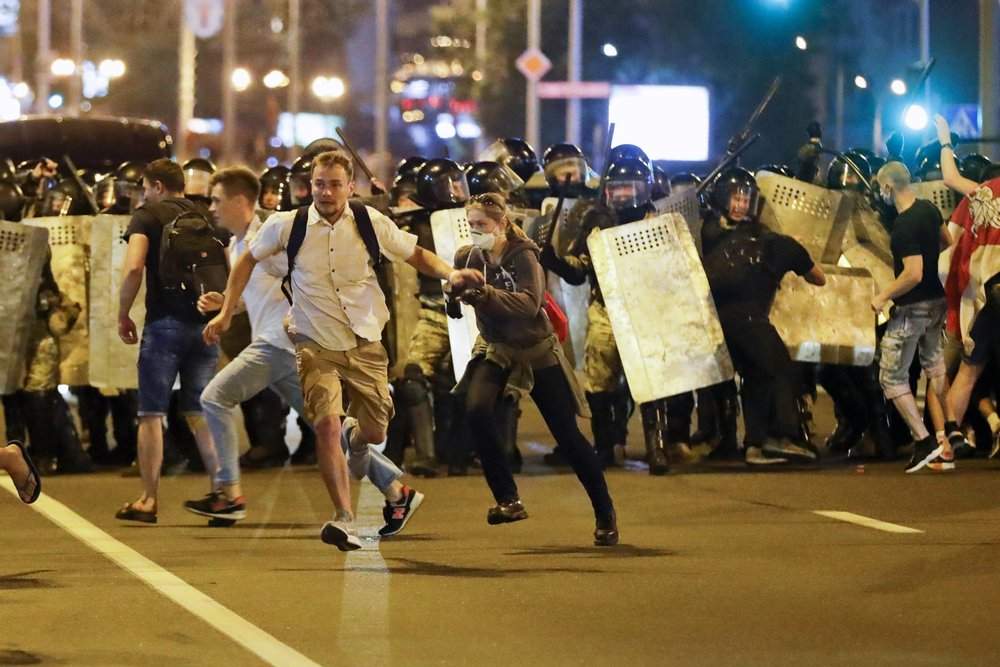 Demonstrators run away from police as they gather to protest against a result of the Belarusian presidential election in Minsk, Belarus, Sunday, Aug. 9, 2020.