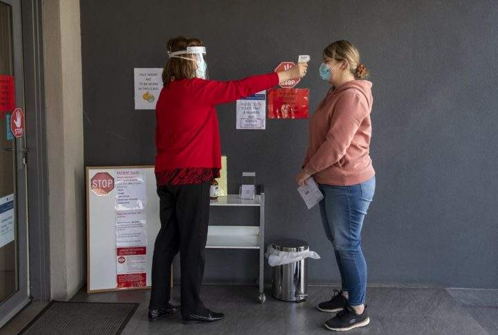 A patient has her temperature checked at a medical clinic during lockdown due to the continuing spread of the coronavirus in Melbourne, Thursday, Aug. 6, 2020. V=.