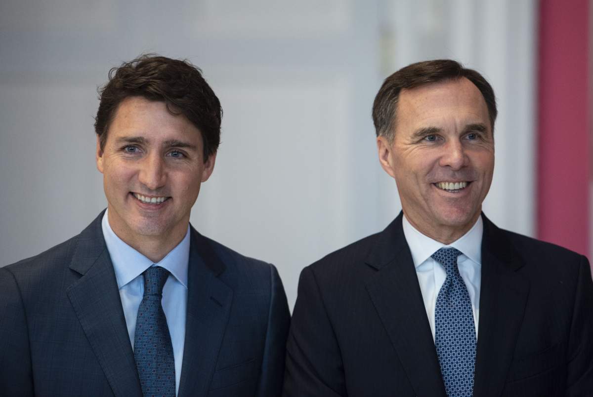 Prime Minister Justin Trudeau stands with Bill Morneau as he remains Minister of Finance during the swearing in of the cabinet at Rideau Hall in Ottawa in a Nov. 20, 2019, file photo. 