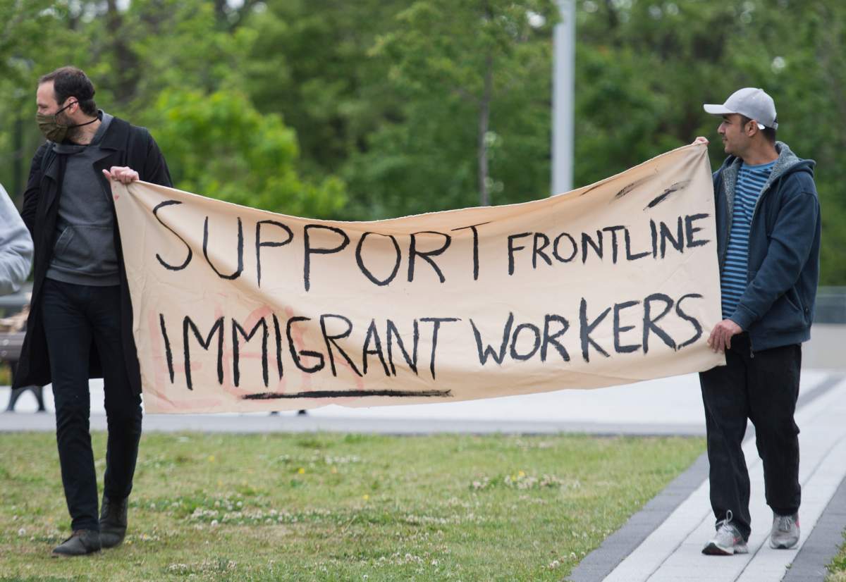 FILE: People hold up  a sign during a Dollarama workers protest calling for better pay and working conditions in Montreal, Saturday, June 13, 2020, as the COVID-19 pandemic continues in Canada and around the world. 