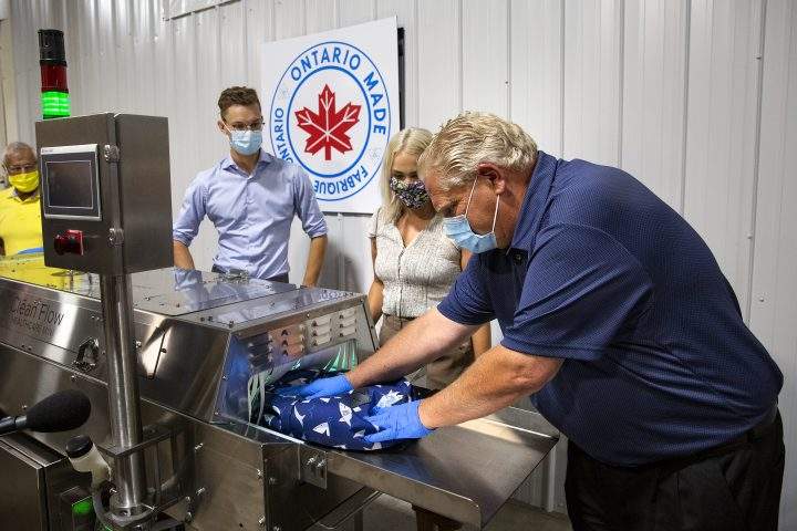 Ontario Premier Doug Ford pushes a children’s backpack through a sanitization machine at Clean Works Corp. in Beamsville, Ont., on Tuesday, Aug. 4, 2020.