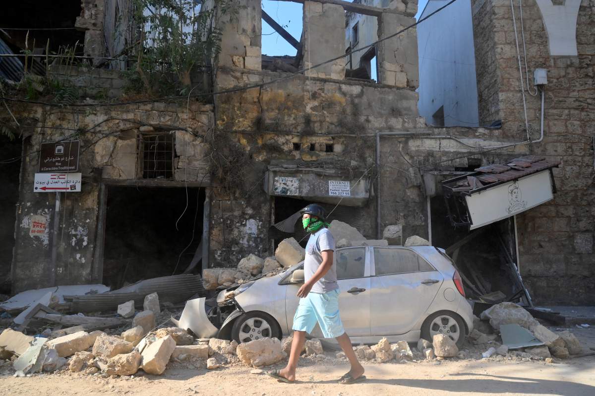 A man walks next to a damaged vehicle in the aftermath of a massive explosion in Beirut, Lebanon, Aug. 5 2020. EPA/WAEL HAMZEH/via CP