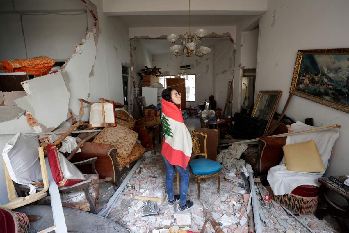 Farah Mahmoud, wrapped in Lebanese national flag, checks her parents destroyed apartment after Tuesday’s explosion in the seaport of Beirut, Lebanon, Aug. 6, 2020.