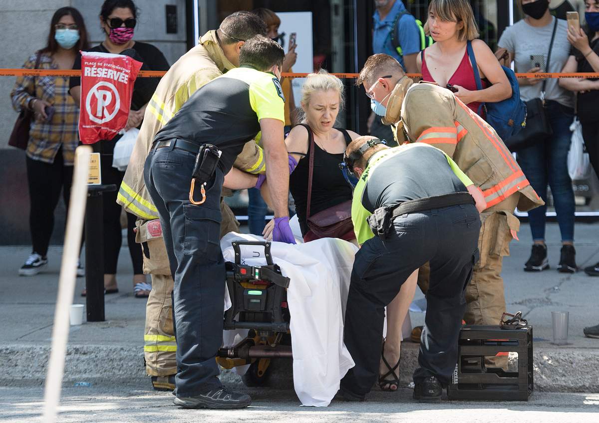 A woman is helped onto a stretcher by paramedics after a jeep sped down a pedestrianized zone on Sainte-Catherine Street in Montreal, Saturday, Aug. 8, 2020.