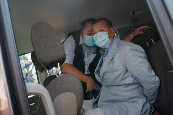 Hong Kong media tycoon Jimmy Lai, right, who founded local newspaper Apple Daily, is arrested by police officers at his home in Hong Kong, Monday, Aug. 10, 2020.