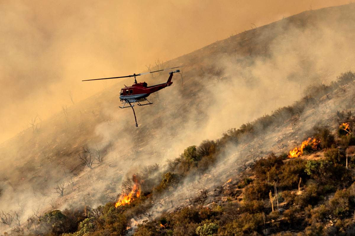 A helicopter prepares to drop water on the Lake Fire burning in the Angeles National Forest north of Santa Clarita, Calif., on Thursday, Aug. 13, 2020. 