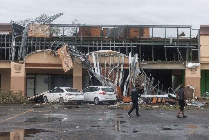 People walk past a destroyed building after the passing of hurricane Laura in Lake Charles, La., on Aug. 27, 2020.