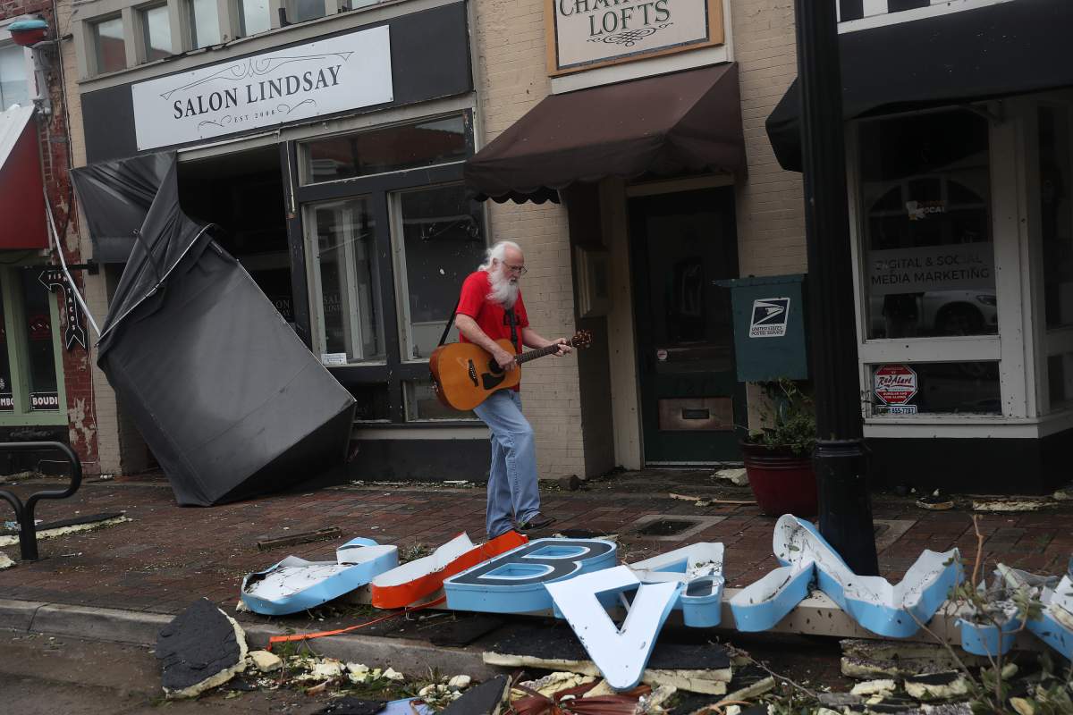Mitch Pickering plays his guitar while walking through the downtown area after hurricane Laura passed through on Aug. 27, 2020 in Lake Charles, La.