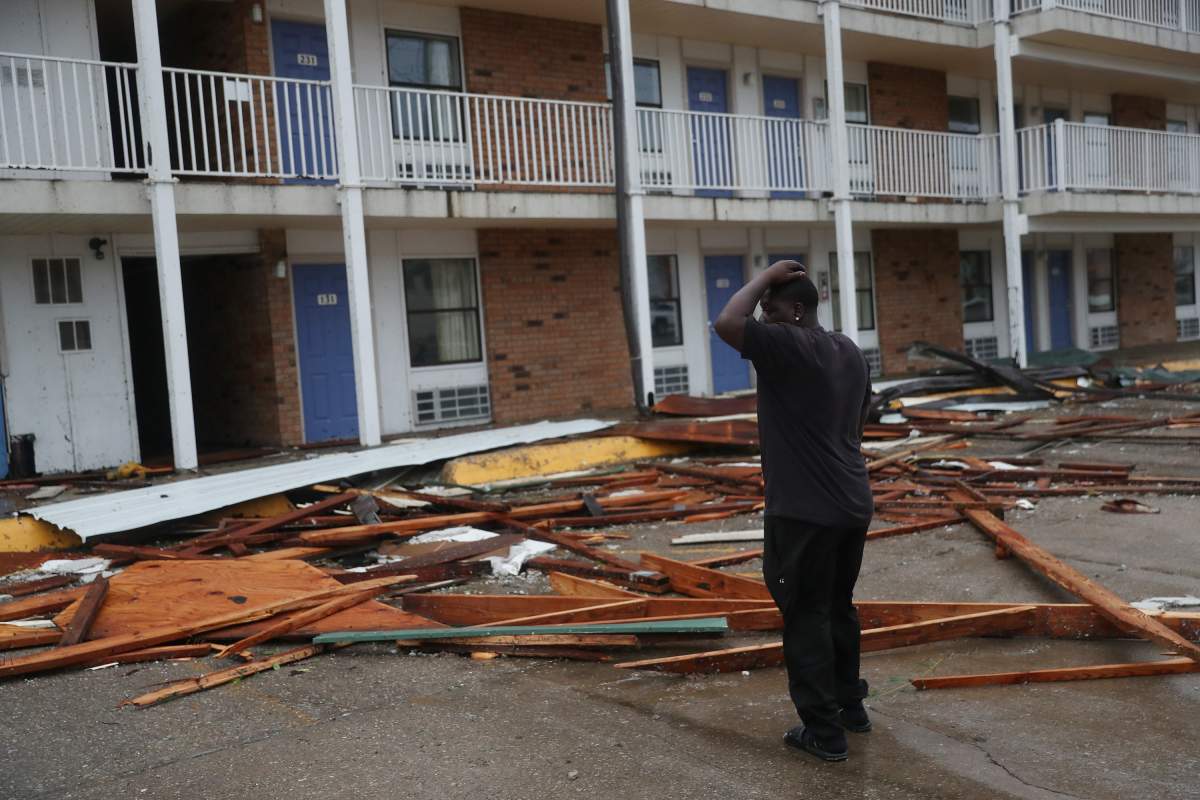A person stands next to a hotel that had parts of its roof blown off as hurricane Laura passed through the area on Aug. 27, 2020, in Lake Charles, La.