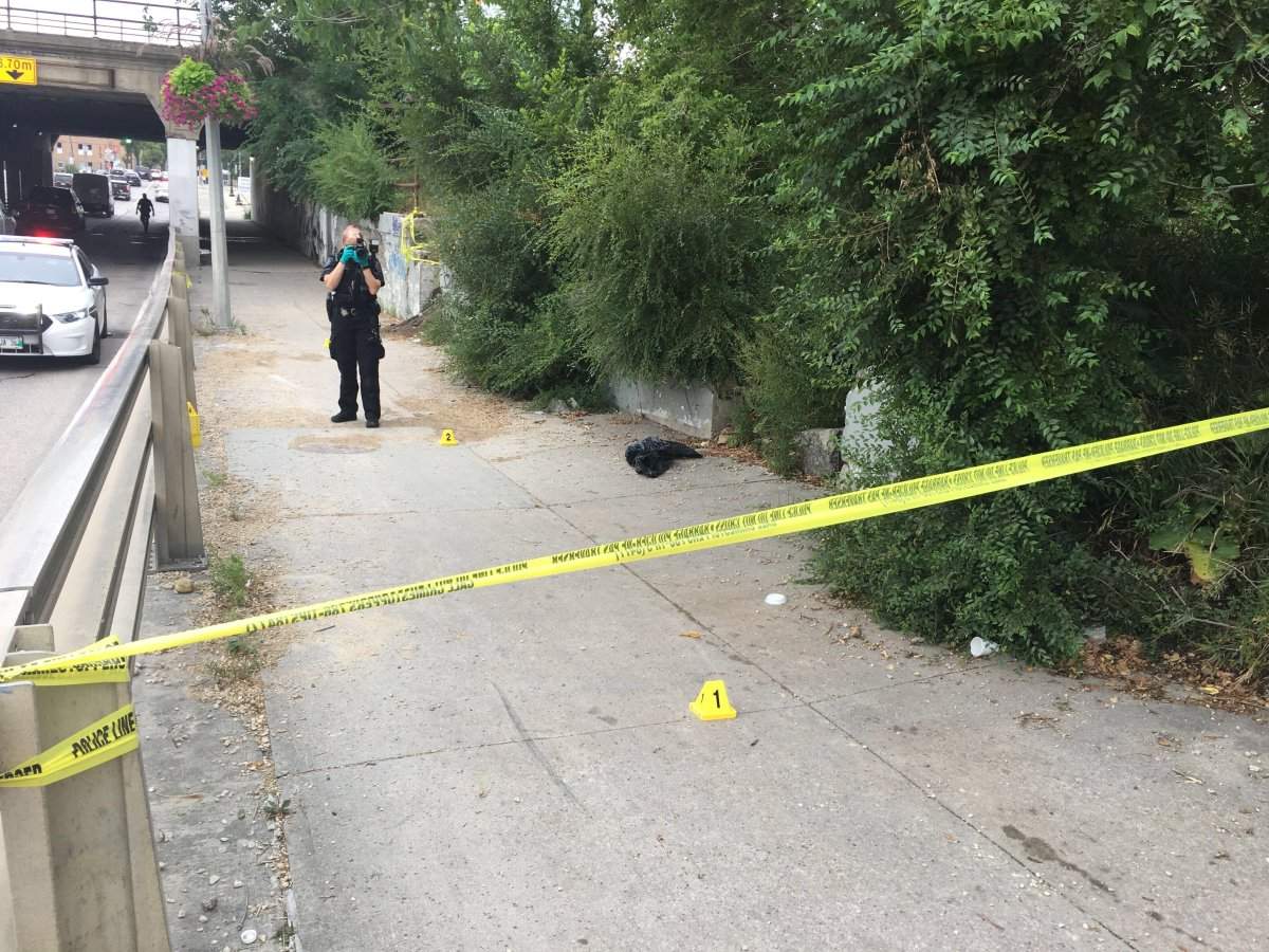 A Winnipeg police officer photographs a crime scene adjacent to the Main Street underpass on August 14, 2020. 
