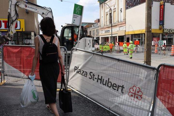 Plaza Saint-Hubert pedestrian walks on temporary pathway while construction continues on St-Hubert Street on Tuesday, Aug. 11, 2020. 