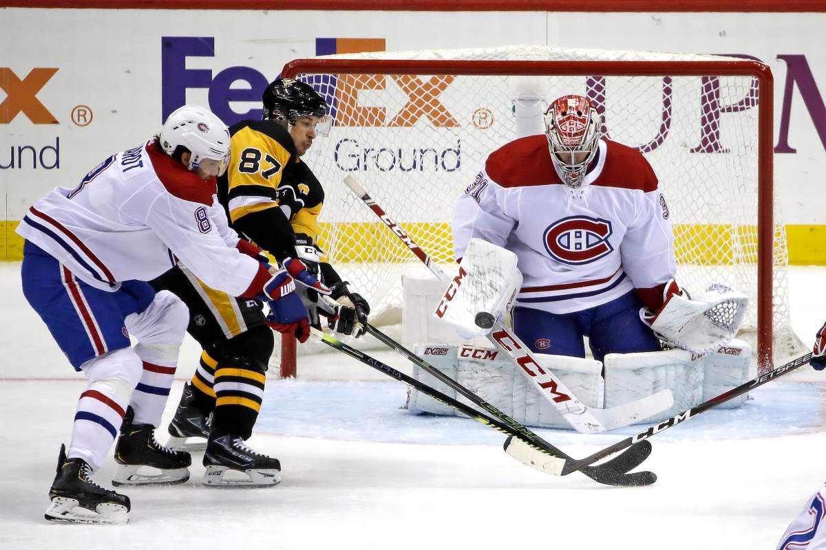 FILE - In this Feb. 14, 2020, file photo, Pittsburgh Penguins' Sidney Crosby (87) can't deflect a shot in front of Montreal Canadiens goaltender Carey Price (31) with Ben Chiarot (8) defending.
