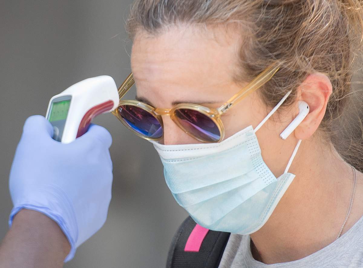 FILE - A woman has her temperature checked prior to entering a store in Montreal on Aug. 1, 2020.