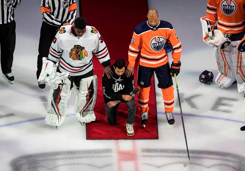 Minnesota Wild’s Matt Dumba takes a knee during the national anthem flanked by Edmonton Oilers’ Darnell Nurse, right, and Chicago Blackhawks’ Malcolm Subban before an NHL playoff game in Edmonton, Saturday, Aug. 1, 2020. THE CANADIAN PRESS/Jason Franson