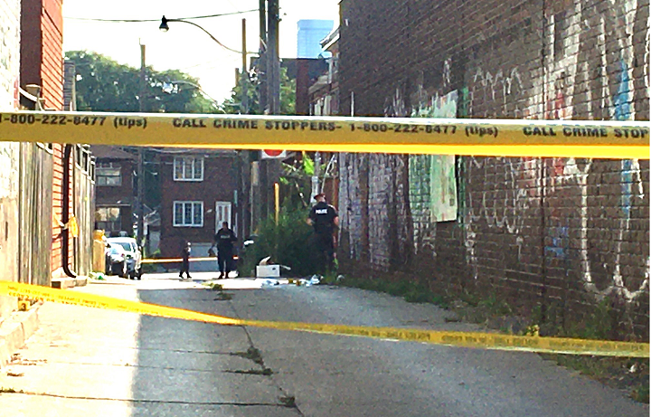 Officers collect evidence in a laneway in the area of Ossington Avenue and Dundas Street Sunday morning.