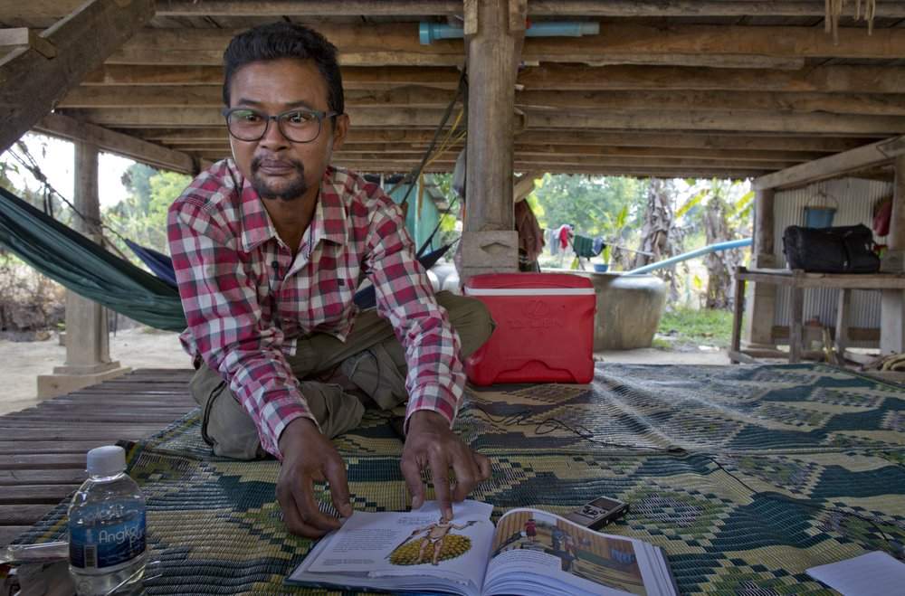 Vannak Anan Prum, who was double trafficked, points to his illustration of an abusive former boss, a palm oil estate owner, in his graphic novel depicting his life as a slave on a fishing boat before being sold onto a Malaysian palm oil plantation, at his home in Pursat, Cambodia, Saturday, March 30, 2019
