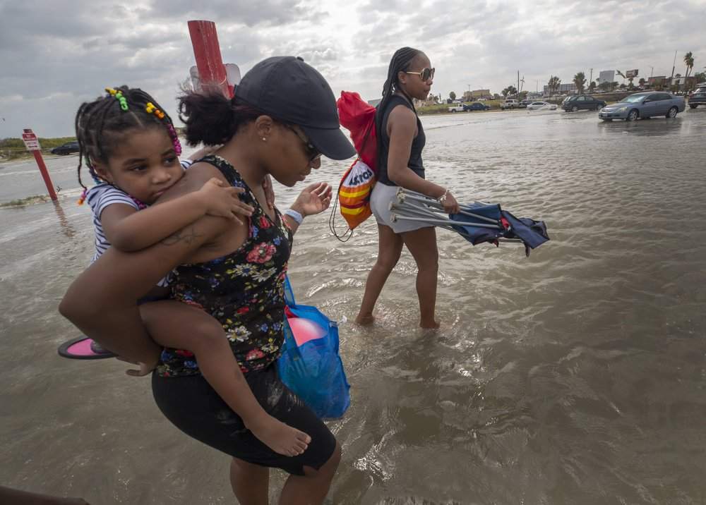 Stacey Young gives her daughter, Kylee Potts, a piggyback ride across the flooding Stewart Beach parking lot in Galveston, Texas on Saturday, Sept. 19, 2020. Tropical Storm Beta continues to move through the Gulf of Mexico and is expected to bring tidal surge and heavy rain to the area. 