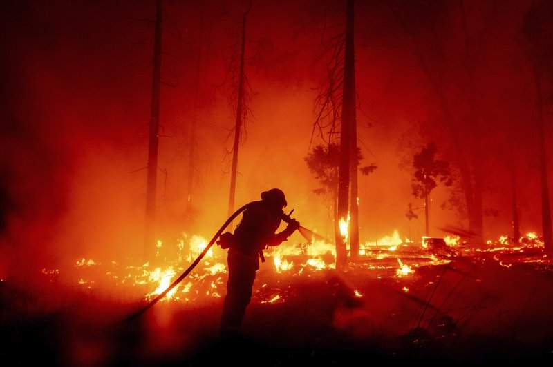 FILE - In this Sept. 7, 2020, file photo, a firefighter battles the Creek Fire as it threatens homes in the Cascadel Woods neighborhood of Madera County, Calif. This year's fires have taxed the human, mechanical and financial resources of the nation's wildfire fighting forces to a degree that few past blazes did. And half of the fire season is yet to come. 