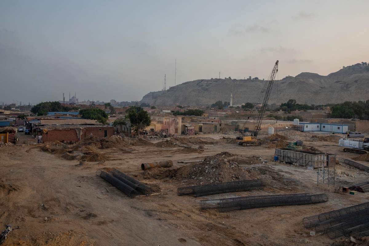 Construction work continues on a highway flyover in a portion cleared of graves in the City of Dead in Cairo, Egypt, with the Citadel, a medieval fortress, visible in the distance on July 29, 2020. Authorities say no ancient monuments were damaged in the construction, but preservationists are mourning the destruction to an urban fabric that was intact for centuries. (AP Photo/Nariman El-Mofty)