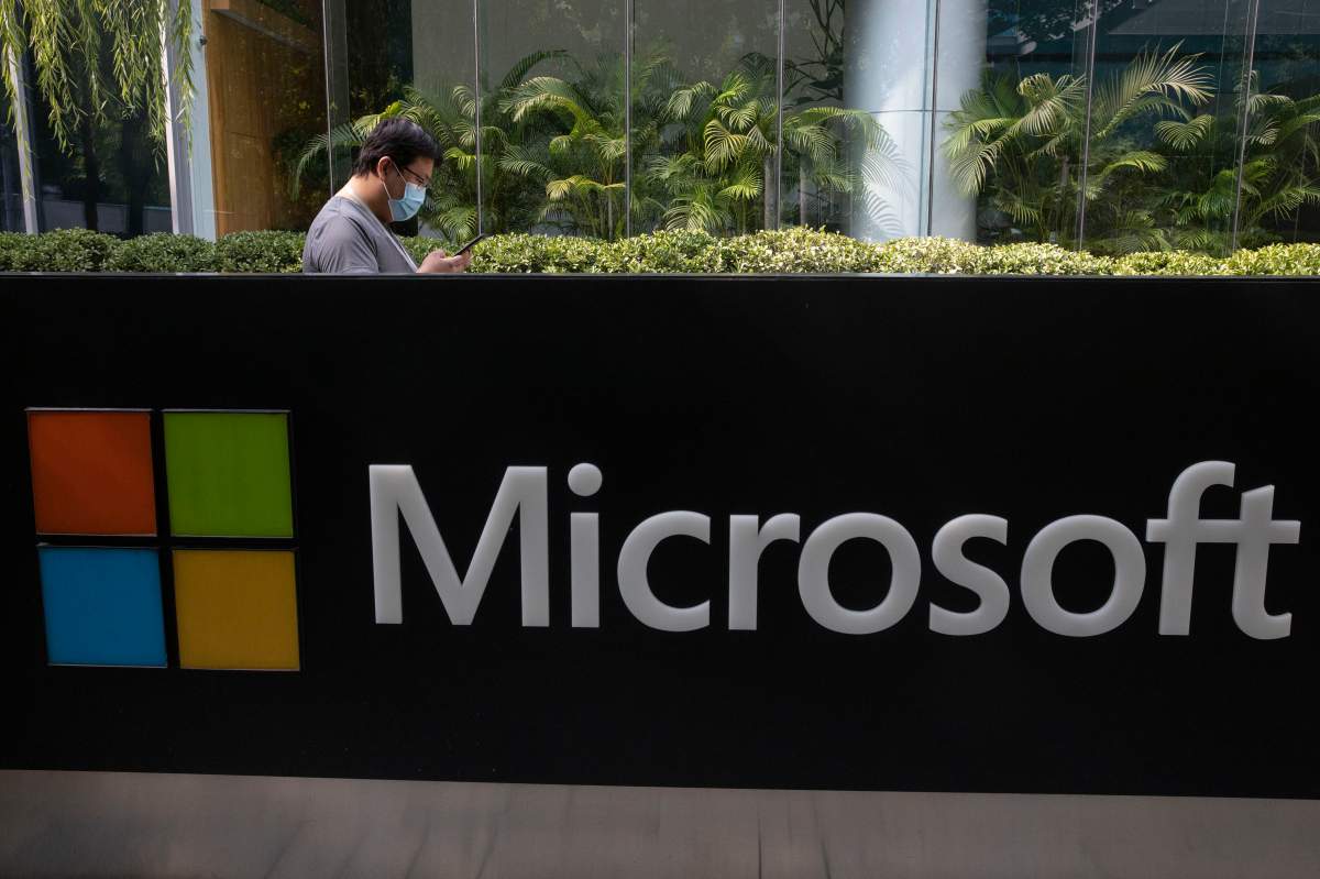 A man wearing a mask looks at this phone outside the Microsoft office in Beijing, China on Friday, Aug. 7, 2020.