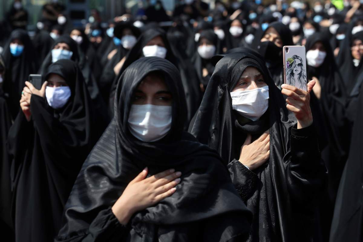 FILE - In this Sunday, Aug. 30, 2020 file photo, people wearing protective face masks to help prevent spread of the coronavirus mourn during an annual ceremony commemorating Ashoura in Tehran, Iran.