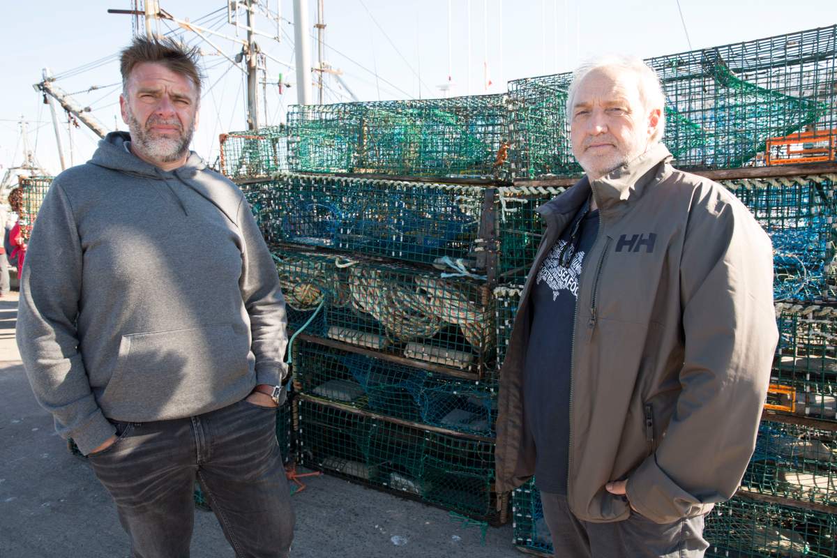Colin Sproul, president of the Bay of Fundy Inshore Fishermen’s Association, Left, and Bernie Berry, president of the Cold Water Lobster Coalition, pose in front of lobster traps that were seized in Saulnierville, N.S., on Sept. 20, 2020. A flotilla of non-Indigenous fishing boats moved into St. Marys Bay off western Nova Scotia on Sunday to remove lobster traps set by fishermen from the Sipekne’katik First Nation.