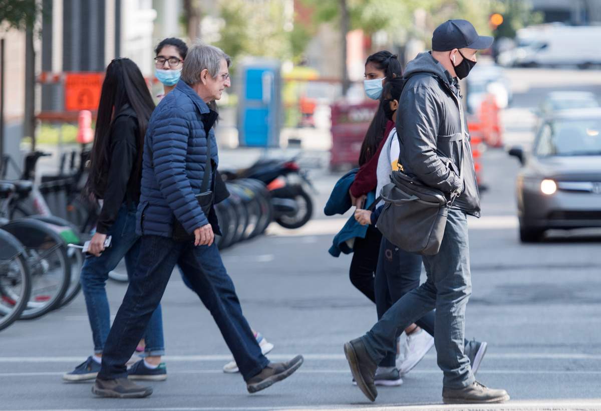 Some wear face masks as they walk along a street in Montreal, Monday, September 21, 2020, as the COVID-19 pandemic continues in Canada and around the world. 