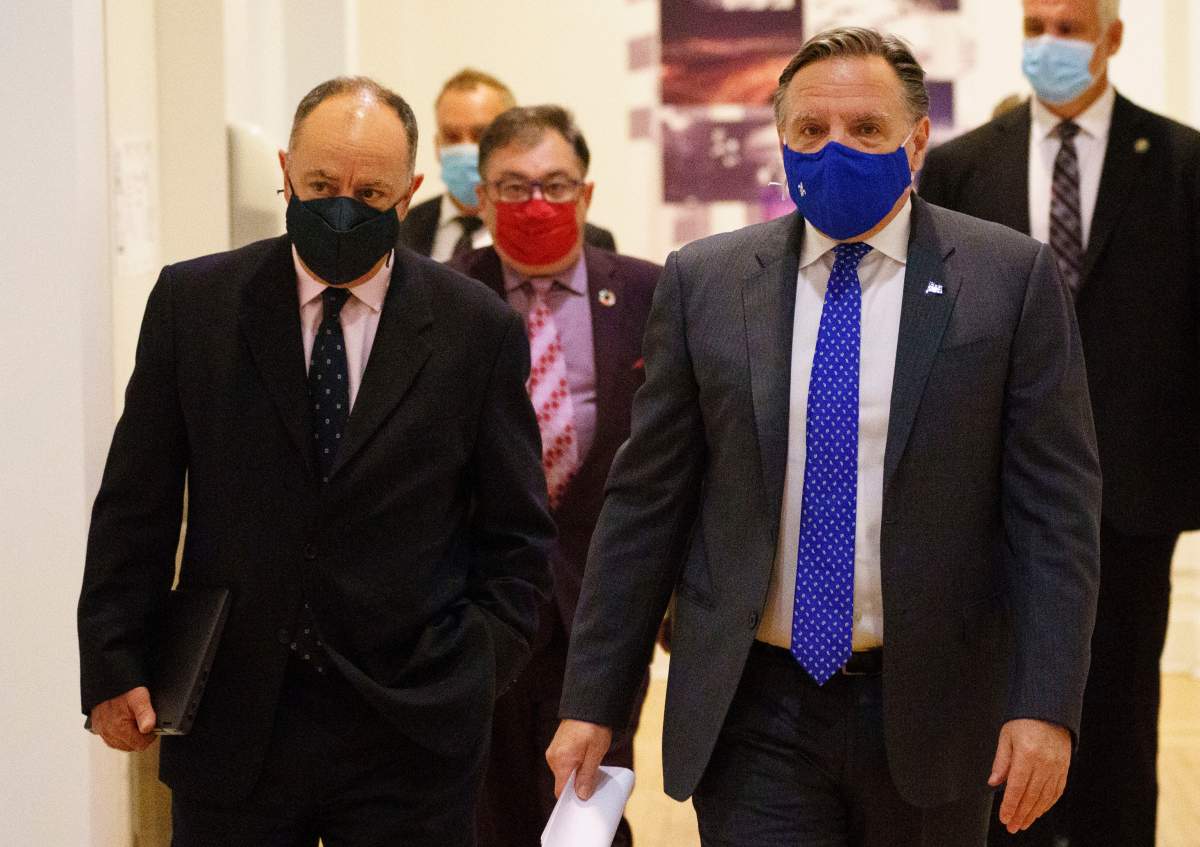Quebec Premier Francois Legault arrives at a news conference flanked by Health Minister Christian Dube, left and Dr. Horacio Arruda, Quebec's director of public health, in Montreal, on Monday, September 28, 2020. 
