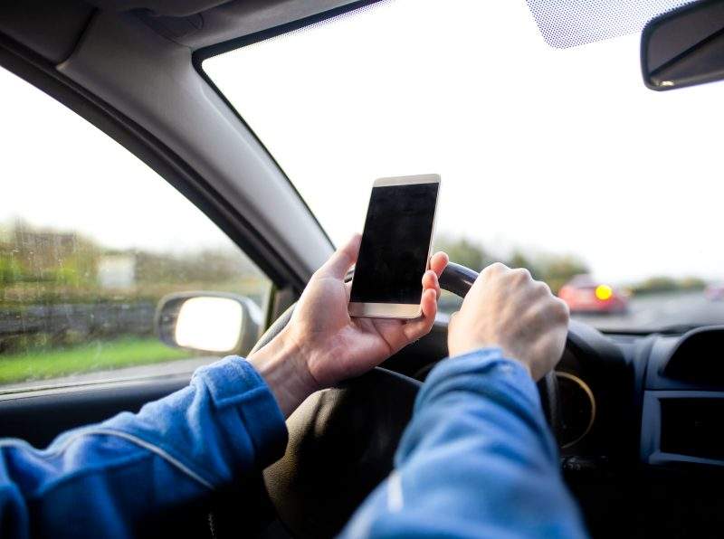 Man using smartphone whilst driving.