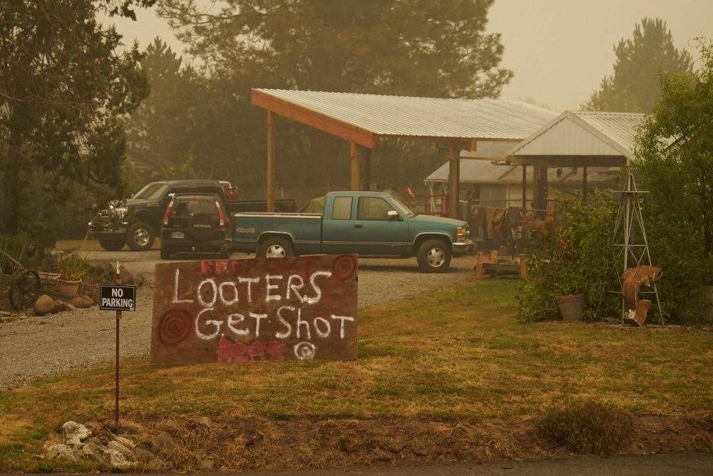 A sign warns that ‘Looters get shot’ at a home near the Riverside Fire, Sunday, Sept. 13, 2020, near Molalla, Ore.