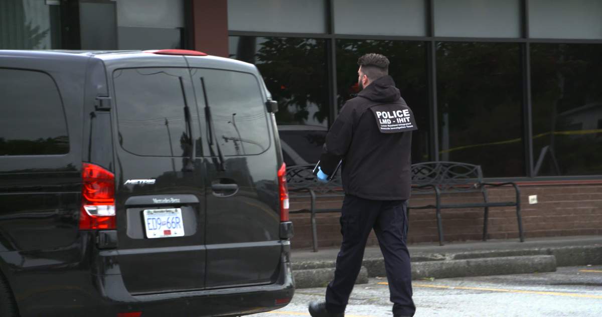 A homicide detective walks past Paul Jin’s van at the scene of the shooting in Richmond.